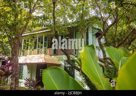 Langkawi, Malaysia - 7. Juni 2022: Traditionelles malaiisches Holzhaus zwischen tropischer Vegetation. Typisches malaysisches Stelzenhaus. Die Holzarchitektur kühlt Stockfoto