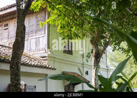 Langkawi, Malaysia - 7. Juni 2022: Traditionelles malaiisches Holzhaus zwischen tropischer Vegetation. Typisches malaysisches Stelzenhaus. Die Holzarchitektur kühlt Stockfoto