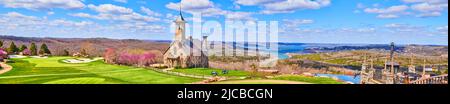 Atemberaubendes Panorama von Golfplatz und Kirche auf Hügeln neben Seen im Frühjahr Stockfoto