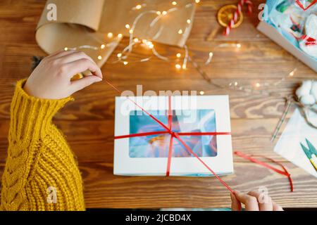Draufsicht auf die Hände der Frau in der Geschenkschachtel zum Öffnen des Pullovers. Stockfoto