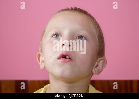 Junge schaut mit einem schmutzigen Gesicht und ohne Vorderzähne auf Stockfoto