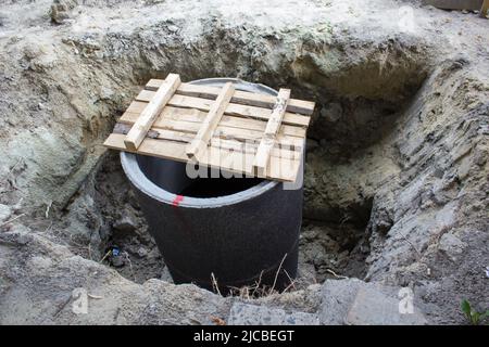 Aushubfirma, die eine Steigleitung an einem Schachtgewölbe an einem Sanitärabwassernsystem in einer neuen kommerziellen Entwicklung installiert Stockfoto