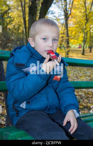 Entzückender kleiner Junge, essen Schokolade Bar Herbst im Park Stockfoto