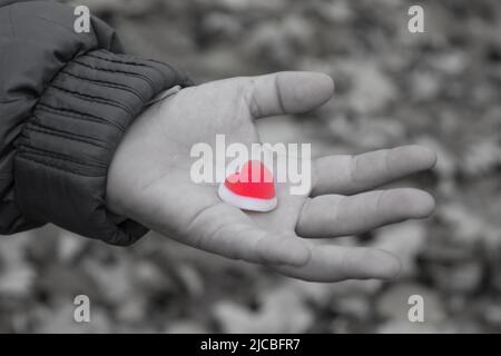 Schenken Sie Frieden das Herz eines Kindes in der Handfläche eines kleinen roten Herzens Stockfoto