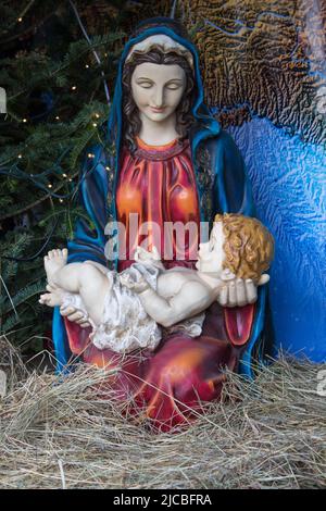 Die Muttergottes hält Jesus an Weihnachten in der Krippe an den Händen Stockfoto