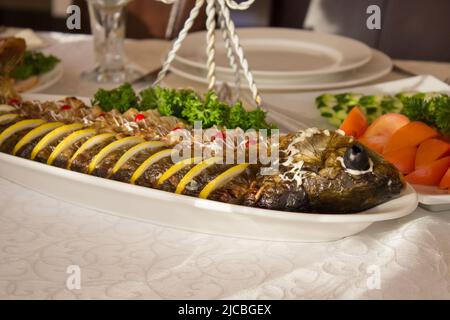 Gefüllter Fisch mit Salat auf dem Tisch im Restaurant Stockfoto