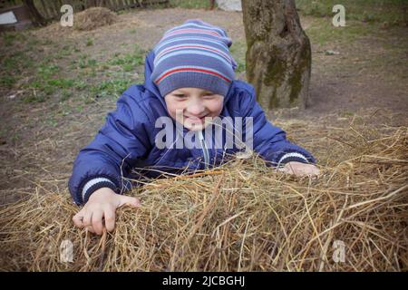 Junge spielt und klettert auf dem Bauernhof auf Heu Stockfoto