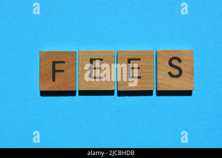 Gebühren, Wort in Holzbuchstaben isoliert auf blauem Hintergrund Stockfoto