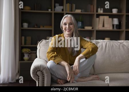 Wunderschöne reife langhaarige Frau entspannen sich auf dem Sofa zu Hause Stockfoto