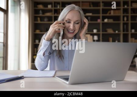 Attraktive ältere Geschäftsfrau, die im Büro arbeitet, genießt Geschäftsanruf Stockfoto