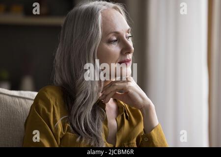 Ältere Frau schaut tief in angenehme Erinnerungen und Gedanken Stockfoto