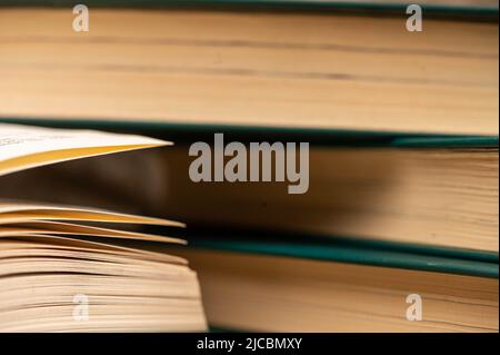 Ein Stapel Bücher und ein offenes Buch auf dem Tisch. Nahaufnahme, selektiver Fokus. Stockfoto