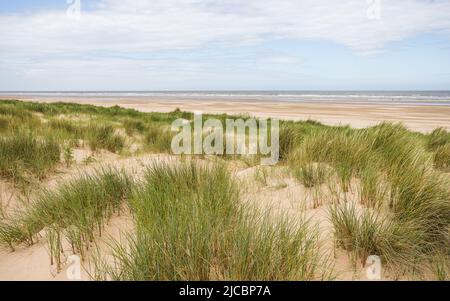 Ainsdale Beach, der über den Sanddünen mit Marrammgras an der Küste von Sefton in der Nähe von Southport abgebildet ist. Stockfoto