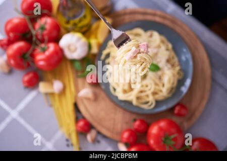 Hausgemachte Pasta Carbonara mit frischem Basilikum und Parmesan in Keramikschale Stockfoto