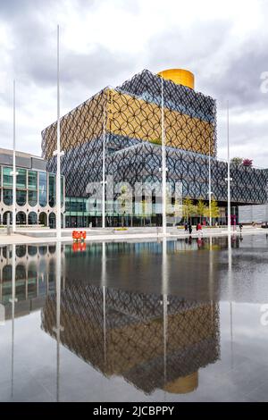 Die Library of Birmingham ist ein ikonisches Gebäude am Centenary Square im Stadtzentrum von Birmingham. Sie spiegelt sich hier in der angrenzenden Wasseroberfläche wider. Stockfoto