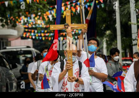 Manila, Philippinen. 12.. Juni 2022. Philippinisch-katholischer Priester Fr. Robert Reyes trägt ein hölzernes Kruzifix, da Mitglieder einer religiösen Gemeinde anlässlich des 124.. Jahrestages der Unabhängigkeit der Philippinen in Quezon City, Metro Manila, Philippinen, eine Pilgerfahrt abhalten. 12. Juni 2022. Die Wallfahrt markiert die Dauer des Christentums im Land. (Bild: © Basilio Sepe/ZUMA Press Wire) Stockfoto