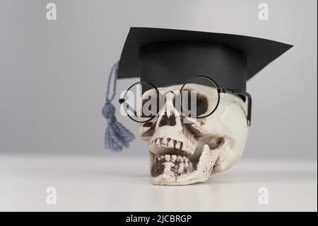 Spielzeug Kunststoff Schädel mit akademischer Kappe und Brille. Stockfoto