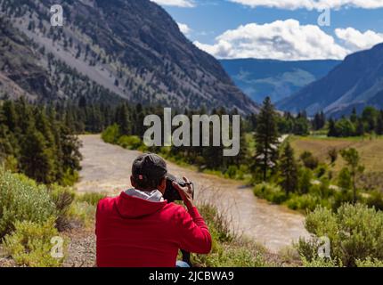 Ein Fotograf, der mit einer Digitalkamera in einem Gebirge fotografiert. Reise- und Active Lifestyle-Konzept. Kreative professionelle Fotografie. Phot Stockfoto