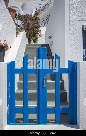 Traditioneller Eingang zu einem griechischen Inselhaus, blaues Tor und weiß getünchte Wände, aufgenommen auf der Insel Santorini. Stockfoto