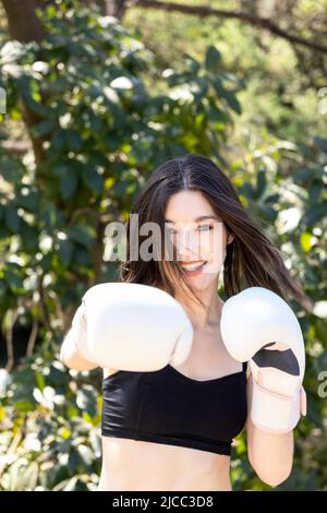 Junge Boxerin mit weißen Handschuhen in einem Park Stockfoto