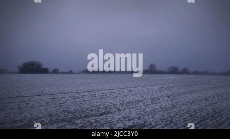 Leichter Schnee auf einem trüben Feld an einem grauen Tag Stockfoto
