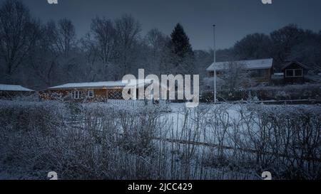 Gemütliche Hygge-Hütte im Winterschneelwald Weihnachtslichter Stockfoto