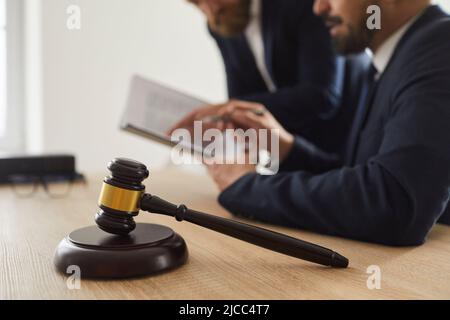 Nahaufnahme des Richters Gavel, der auf einem Schallblock auf dem Tisch vor dem Hintergrund des Richters und des Anwalts steht. Stockfoto