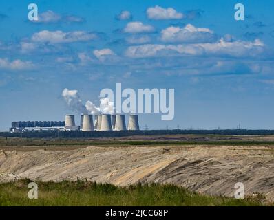 10. Juni 2022, Brandenburg, Grießen: Die Kühltürme des Braunkohlekraftwerks Jänschwalde sind hinter den Schaufelhaufen der Tagebaumine Jänschwalde der Lausitz Energie Bergbau AG (LEAG) zu sehen. Die Lausitzer Naht von 2. wird in der Tagebaumine Jänschwalde abgebaut. Hier werden jährlich rund elf Millionen Tonnen Braunkohle abgebaut. Die Förderbrücke F60 und mehrere Schaufelradbagger bewegen die Lausitzer Erde seit 1976 zu diesem Zweck. Die Braunkohle wird zur Stromerzeugung im nahegelegenen Kraftwerk Jänschwalde verbrannt. Das Kraftwerk soll genommen werden Stockfoto