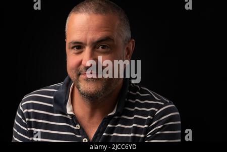 Lächelnder hispanischer Mann mit einer Augenbraue, die auf einem schwarzen Hintergrund mit Kopierfläche angehoben wurde Stockfoto