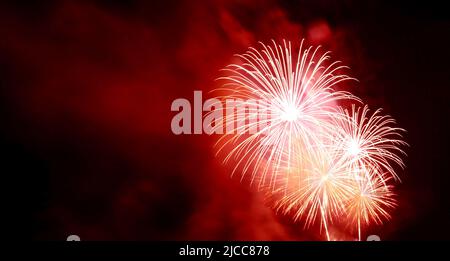 Spektakuläres scharlachrot gefallenes Feuerwerk, das am Nachthimmel planscht Stockfoto