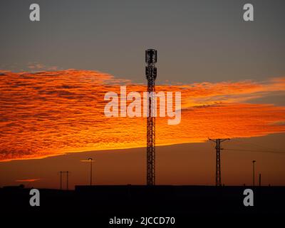 Kommunikationsantenne in einem orangefarbenen Himmel. Technologiekonzept Stockfoto