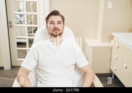 Mann sitzt auf einem Stuhl in der Klinik für ästhetische Medizin Stockfoto