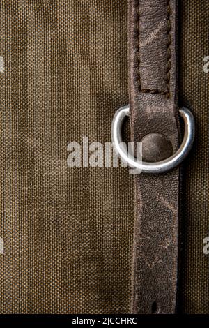 Nahaufnahme Textur eines Rucksack aus Canvas-Stoff. Lederriemen und Metallschnallen. Vintage Khaki Hintergrund. Stockfoto