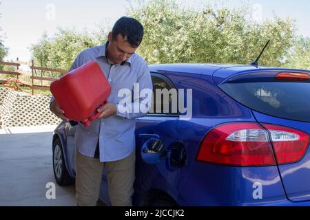 Bild eines Mannes, der seine leere Brieftasche ohne Geld und eine leere Benzinkanister neben dem Autotank hält. Verweis auf den konstanten Anstieg der Stockfoto