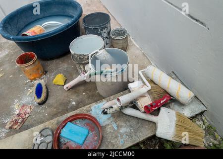 Eine Nahaufnahme von Pinsel, Walzen und Farbschachteln während eines Whitewashs in einem indischen Haushalt. Indien Stockfoto