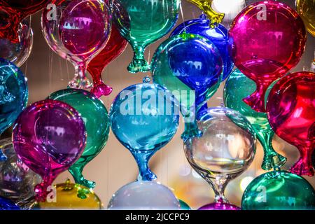 Viele Glasballons in verschiedenen Farben hängen von der Decke Stockfoto