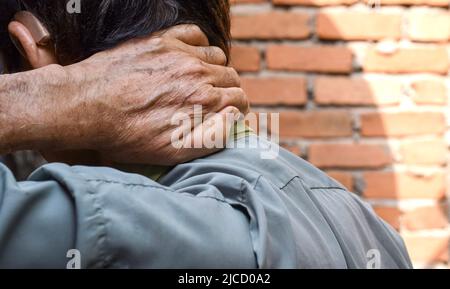 Schmerzen im Nackenmuskel des südostasiatischen älteren Mannes. Konzept von Nackenschmerzen und Nackensteifigkeit. Stockfoto