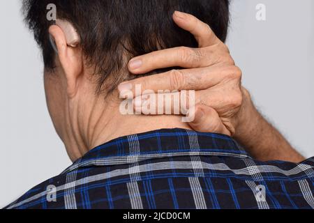 Schmerzen im Nackenmuskel des südostasiatischen älteren Mannes. Konzept von Nackenschmerzen und Nackensteifigkeit. Stockfoto