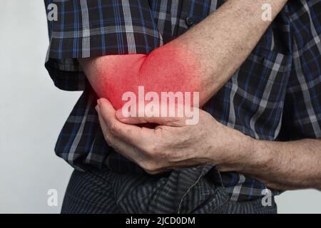 Schmerzen im Ellenbogengelenk des südostasiatischen älteren Mannes. Konzept von Ellenbogenschmerzen, rheumatoider Arthritis und Armproblemen. Stockfoto