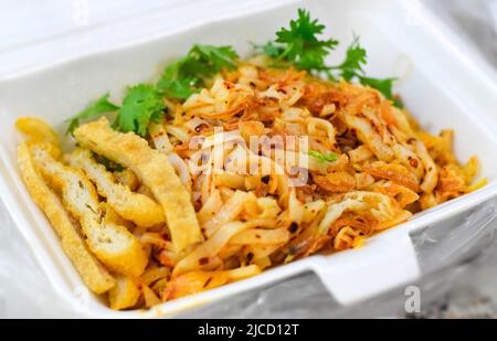 Myanmar traditioneller oder klassischer weißer flacher Nudelsalat namens Khauk SWE Thoke. Nahaufnahme. Stockfoto