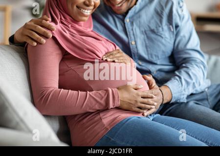 Schwarz schwanger muslim paar zusammen entspannen auf Couch zu Hause Stockfoto