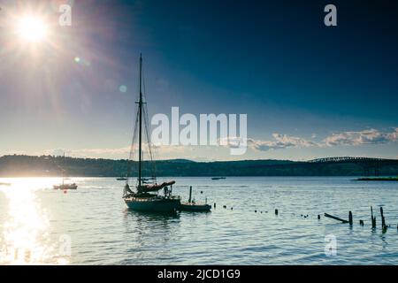 Beacon, NY - USA - 11. Juni 2022 Horizontale Ansicht einer Silhouette eines Segelbootes bei Sonnenuntergang, vor Anker im malerischen Hudson's Long Dock Park am Ban Stockfoto