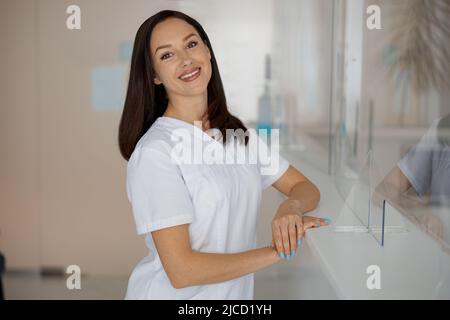 Porträt einer lächelnden Krankenschwester, die in der Nähe der Rezeption in einer medizinischen Klinik steht Stockfoto