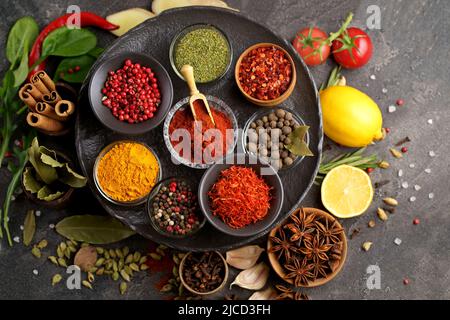 Verschiedene Gewürze ein Jahrgang Löffel auf Stein Tisch. Farbenfroher orientalischer Markt mit Kräutern und Gewürzen. Stockfoto