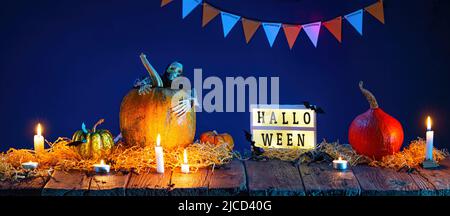 Halloween Hintergrund. Kürbisse und brennende Kerzen auf Holztisch Stockfoto