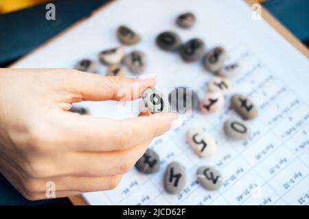 Frau Numerologin Hand mit Kieselstein mit der Nummer sechs 6. Stockfoto