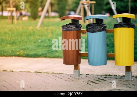 Drei Behälter mit verschiedenen Farben, um das Recycling von Müll zu fördern, konzentrieren sich auf die Behälter und verschwommener Hintergrund Stockfoto