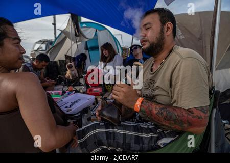 Nakhom Pathom, Thailand. 12.. Juni 2022. Ein Mann raucht Marihuana am zweiten Tag des Marihuana-Festivals „Thailand 420 Legal-AEW“ außerhalb von Nakhom Pathom, Thailand, am Sonntag, dem 12. Juni 2022. Thailand entkriminalisierte vor kurzem Marihuana, was einen Boom im Marihuana-Geschäft ankurbelte. (Bild: © Andre Malerba/ZUMA Press Wire) Stockfoto