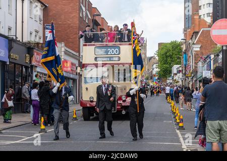 Standardträger der Royal British Legion und ein offener Bus mit Veteranen der Normandie bei der Grand Parade am Victoria Day in Aldershot, Hampshire, Großbritannien Stockfoto