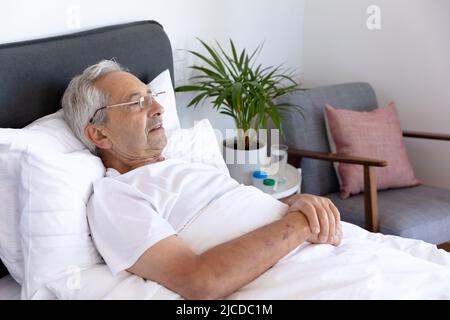 Kaukasischer älterer Mann, der zu Hause auf dem Bett liegt Stockfoto